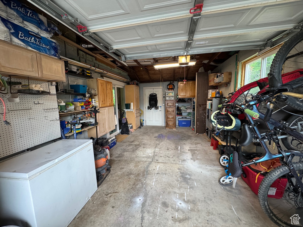 Garage featuring a workshop area, a garage door opener, and fridge