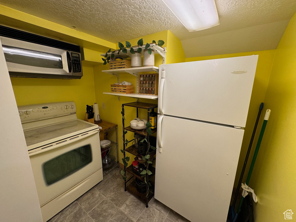 Kitchen with white appliances and a textured ceiling