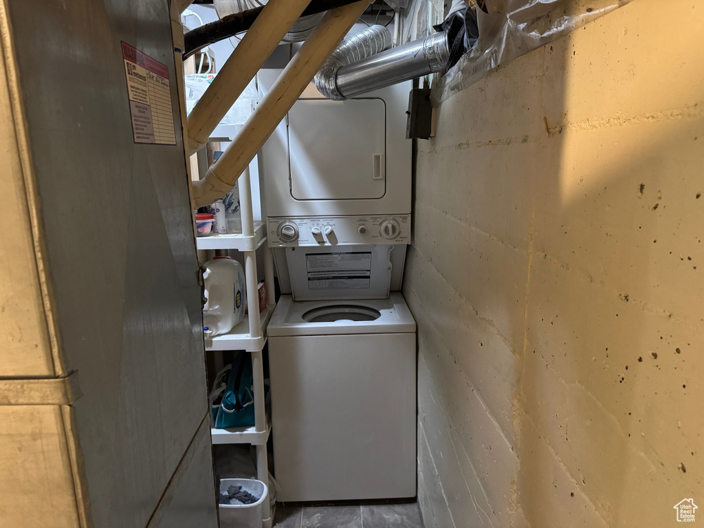 Washroom with stacked washing machine and dryer and concrete block wall