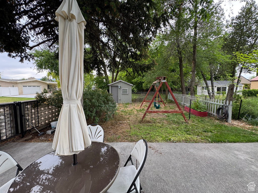 View of patio with a playground and a shed