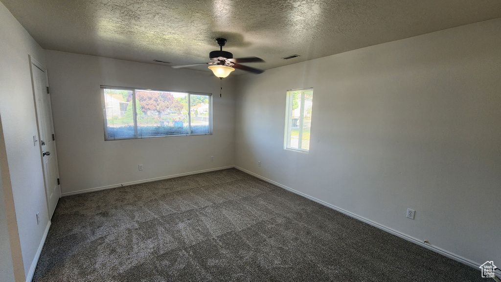 Carpeted spare room with ceiling fan and a textured ceiling