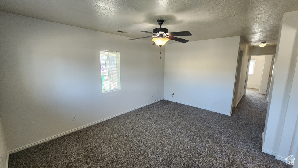 Unfurnished room with dark colored carpet, a textured ceiling, and ceiling fan