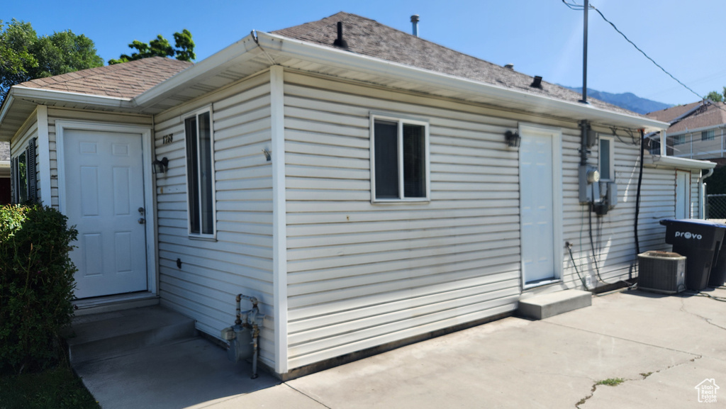 Rear view of house with entry steps, a patio area, and roof with shingles