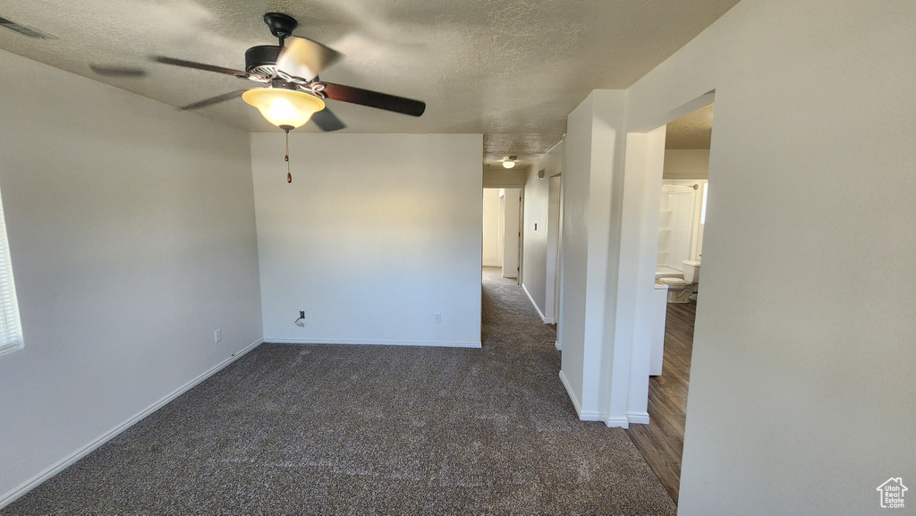 Carpeted empty room featuring ceiling fan and a textured ceiling