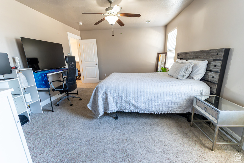 Carpeted bedroom featuring a desk and ceiling fan