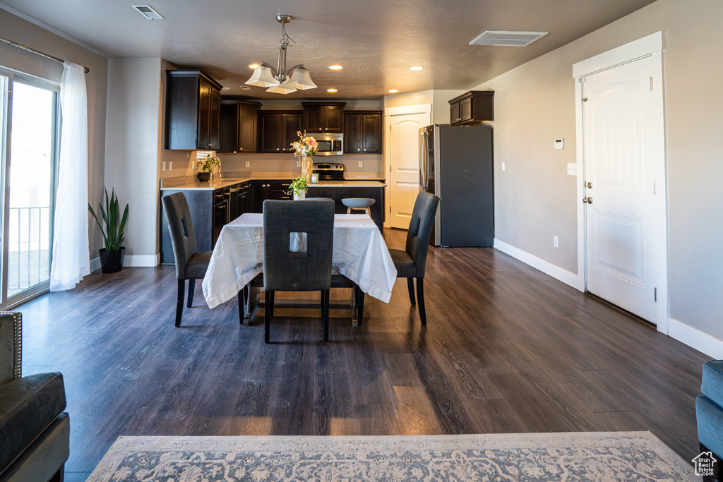 Dining area featuring dark wood finished floors, a chandelier, and recessed lighting