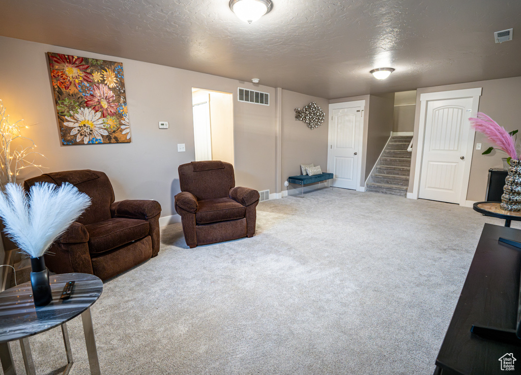 Carpeted living room featuring stairs and a textured ceiling