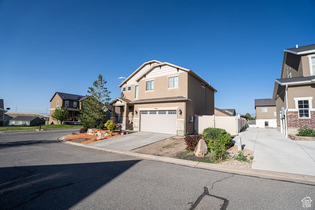 Traditional-style home with driveway, a residential view, stucco siding, and a garage
