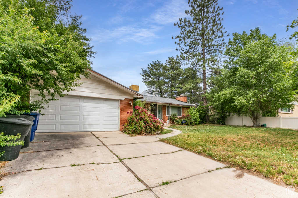 View of front of home with driveway, a chimney, an attached garage, and brick siding