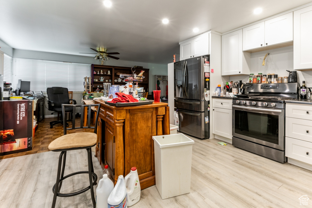 Kitchen featuring appliances with stainless steel finishes, light wood-style floors, white cabinetry, an office area, and recessed lighting