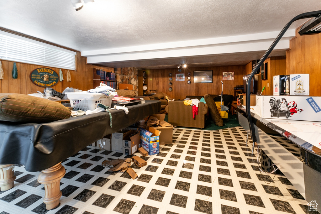 Living area featuring wood walls, tile patterned floors, and a textured ceiling