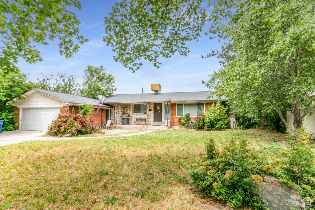 Ranch-style house featuring covered porch, an attached garage, driveway, and a front lawn