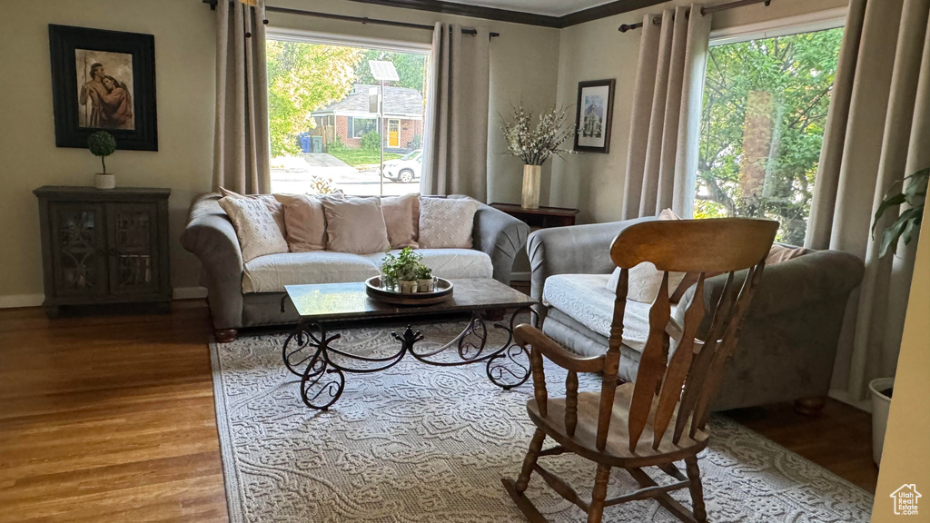 Living area with healthy amount of natural light, wood finished floors, and crown molding