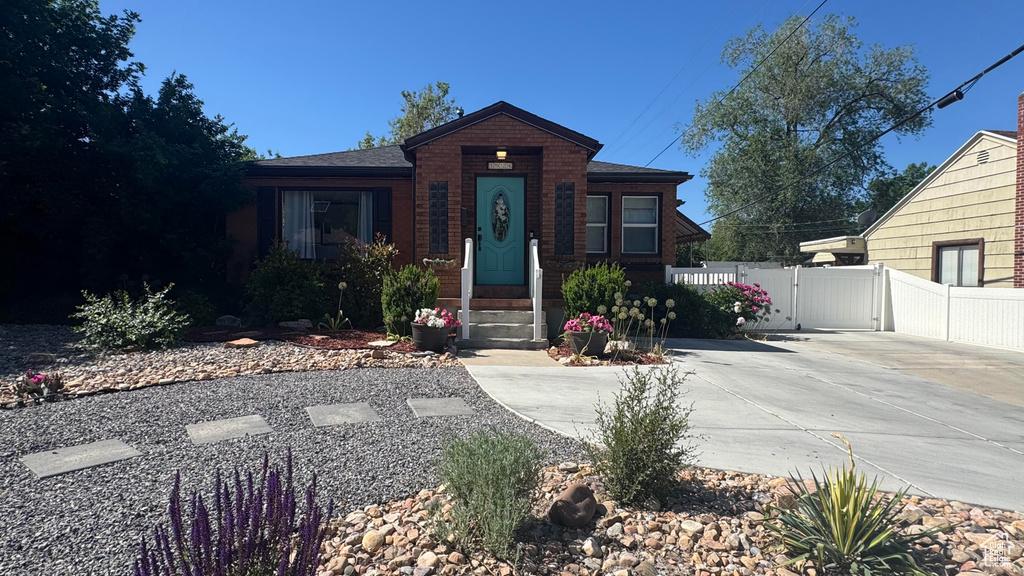 View of front of house featuring concrete driveway, a gate, and brick siding