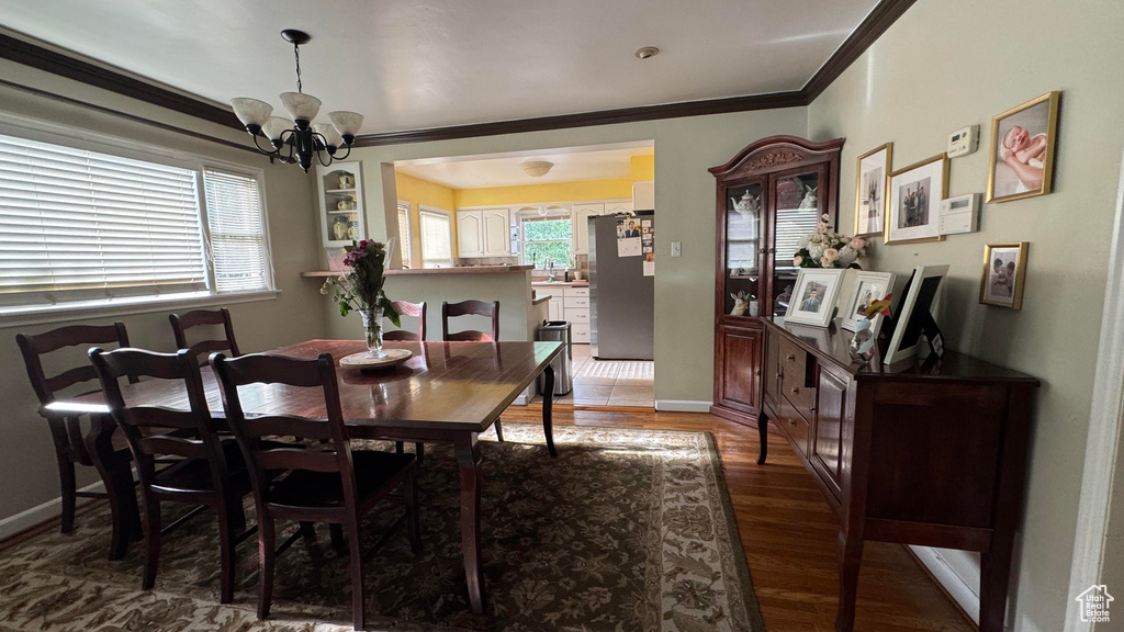 Dining area with a chandelier, crown molding, and wood finished floors