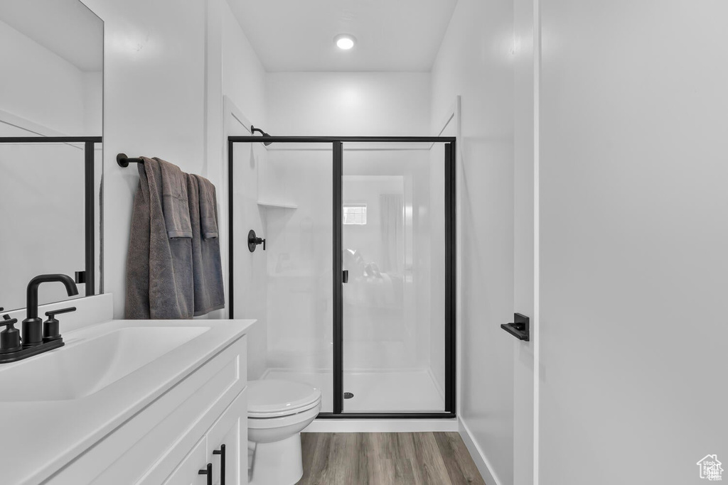 Bathroom with a stall shower, vanity, and wood finished floors