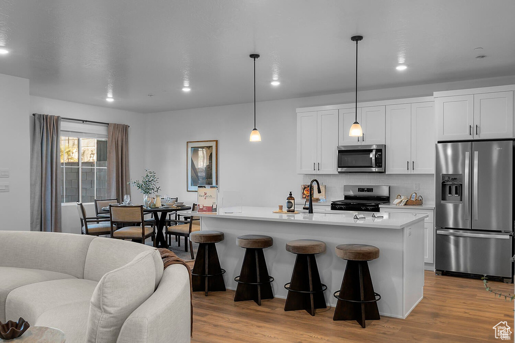 Kitchen with appliances with stainless steel finishes, tasteful backsplash, light countertops, white cabinetry, and recessed lighting