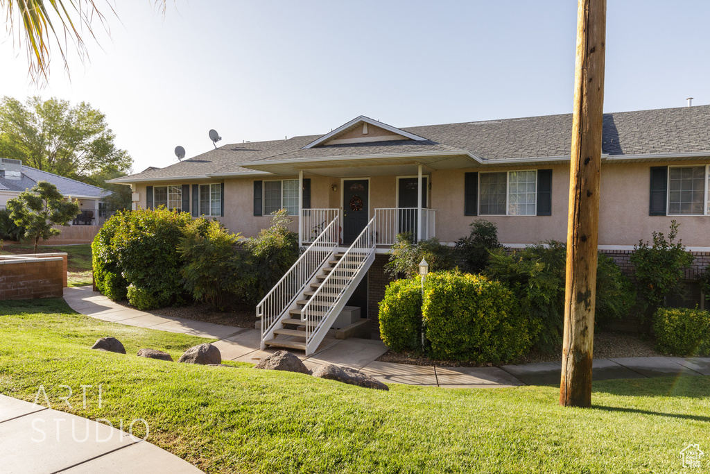 Ranch-style home featuring stucco siding, a front lawn, covered porch, and stairs