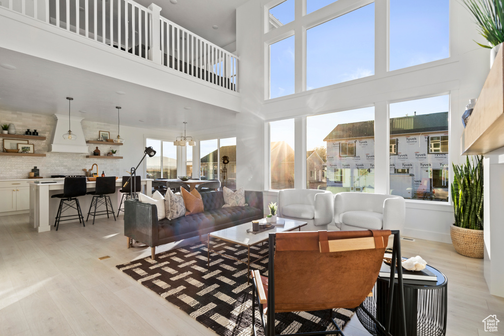 Living room with light wood-style floors, plenty of natural light, and a towering ceiling