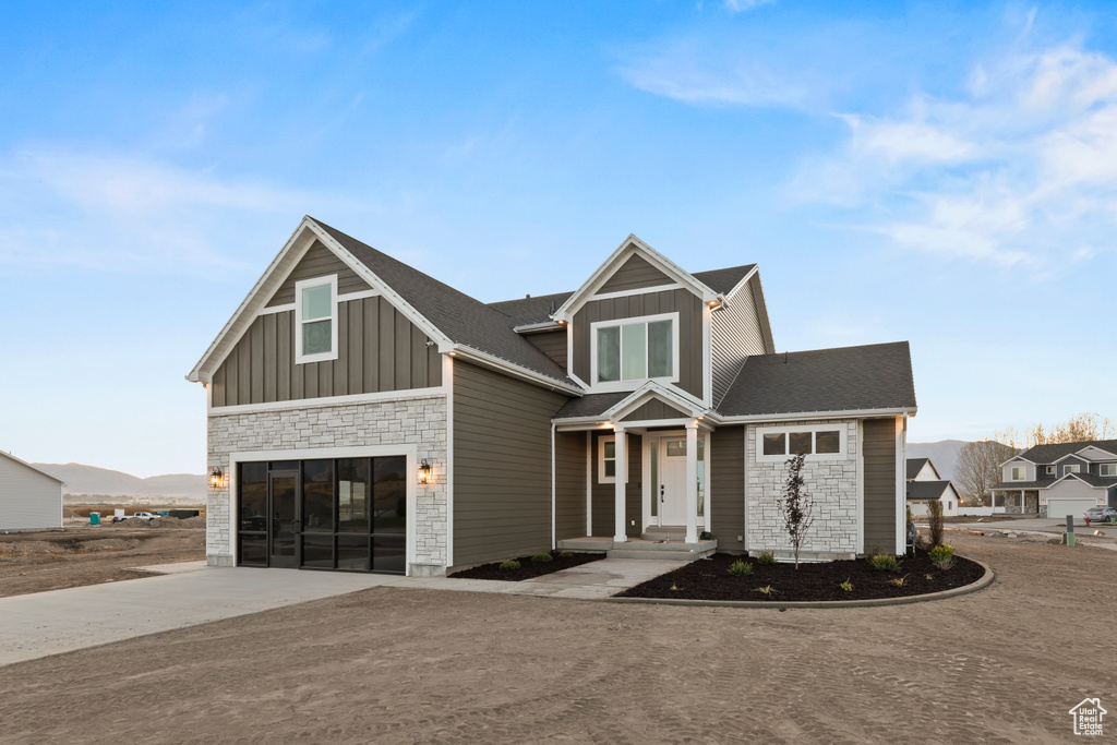 View of front of house featuring board and batten siding, stone siding, an attached garage, and concrete driveway