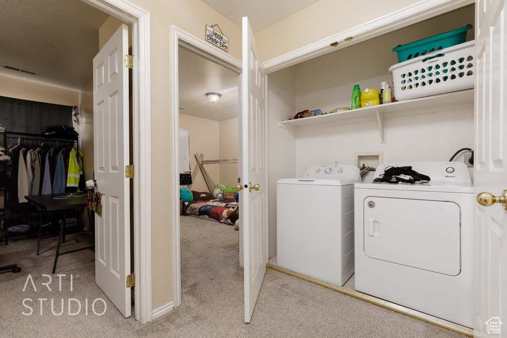 Laundry room featuring washer and dryer and light carpet