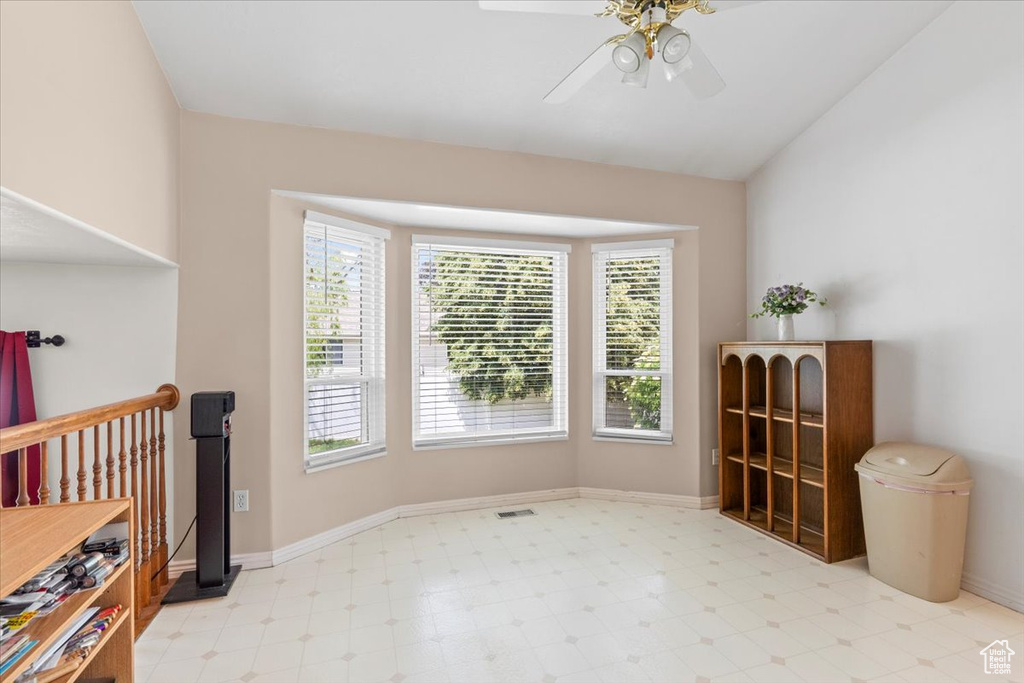 Spare room featuring light flooring, a ceiling fan, and vaulted ceiling