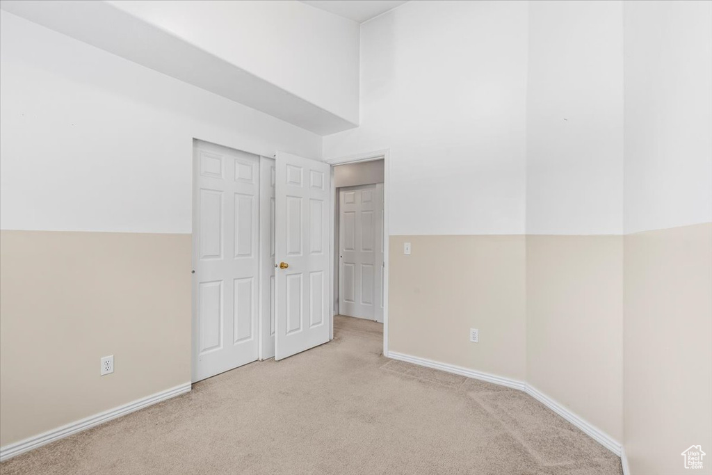 Unfurnished bedroom with light colored carpet and baseboards