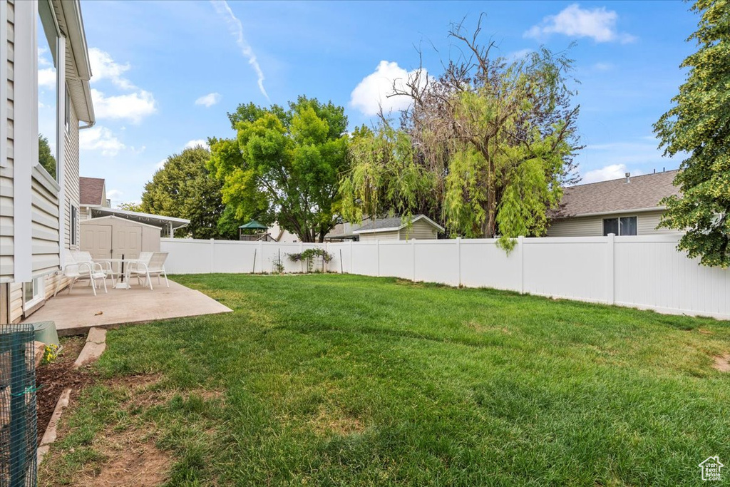 Fenced backyard with a patio and a storage unit