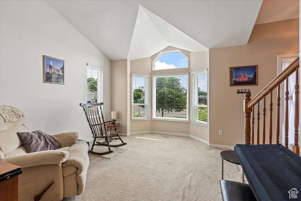 Sitting room with vaulted ceiling, light carpet, and stairs
