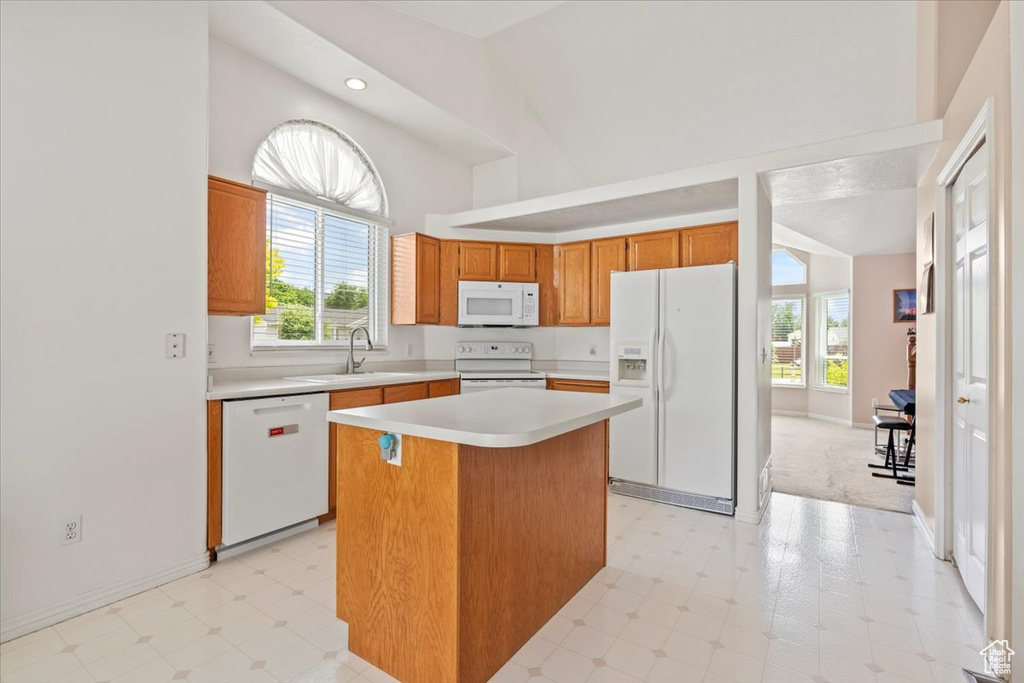 Kitchen with white appliances, a kitchen island, light countertops, light flooring, and a towering ceiling