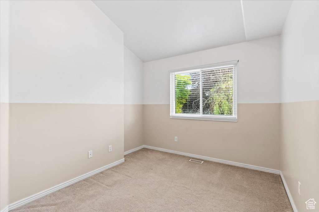 Carpeted empty room featuring lofted ceiling and baseboards
