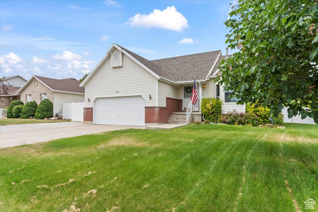 View of front of house featuring brick siding, driveway, a front lawn, roof with shingles, and a garage