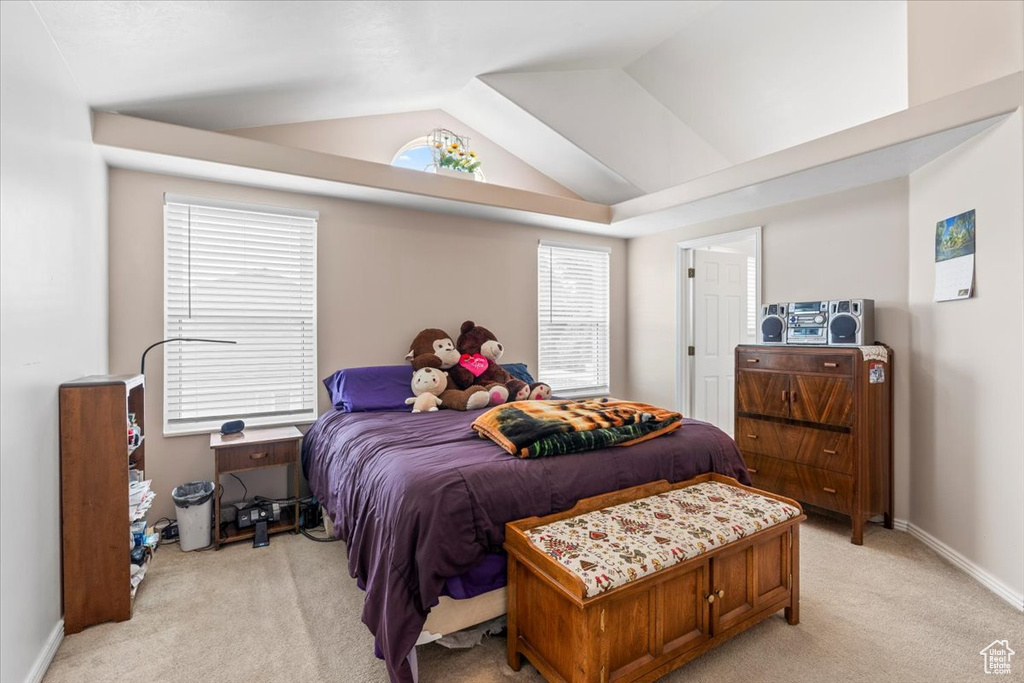 Bedroom with light colored carpet and vaulted ceiling