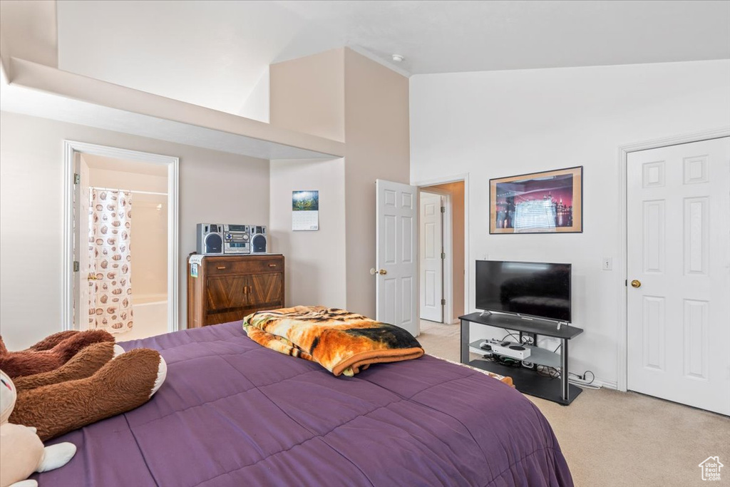 Bedroom featuring light colored carpet, high vaulted ceiling, and ensuite bathroom