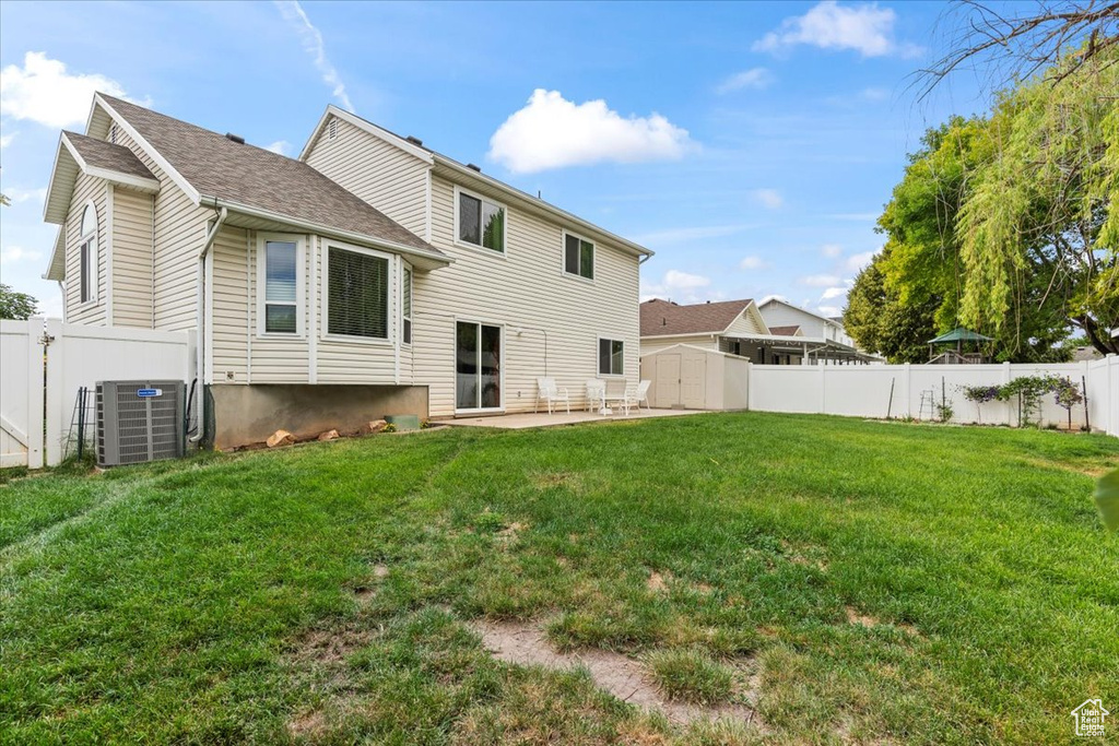 Rear view of house with a shed, a patio, a fenced backyard, and a shingled roof