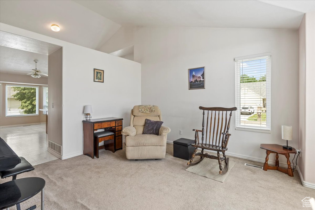 Living area featuring vaulted ceiling, carpet flooring, and ceiling fan