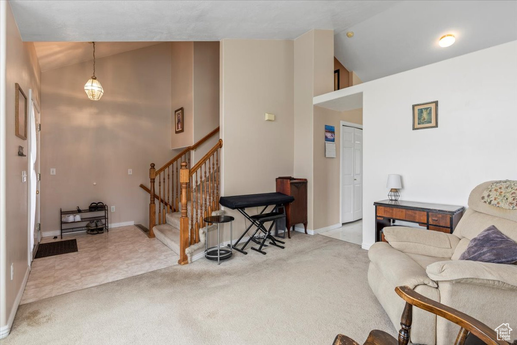 Carpeted living room with stairway and high vaulted ceiling