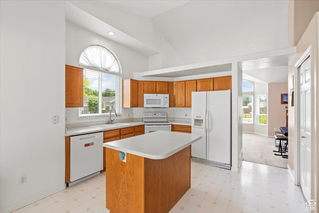 Kitchen with white appliances, light floors, light countertops, brown cabinets, and high vaulted ceiling