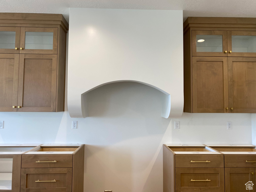 Kitchen featuring glass insert cabinets, light countertops, and brown cabinets