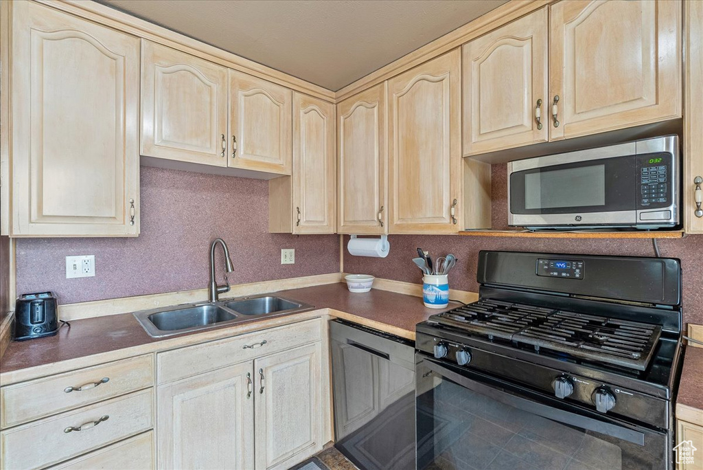 Kitchen with gas stove, stainless steel microwave, light brown cabinetry, and dishwasher