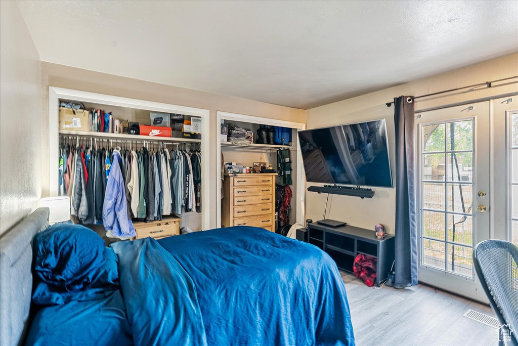 Bedroom featuring wood finished floors, access to exterior, and two closets