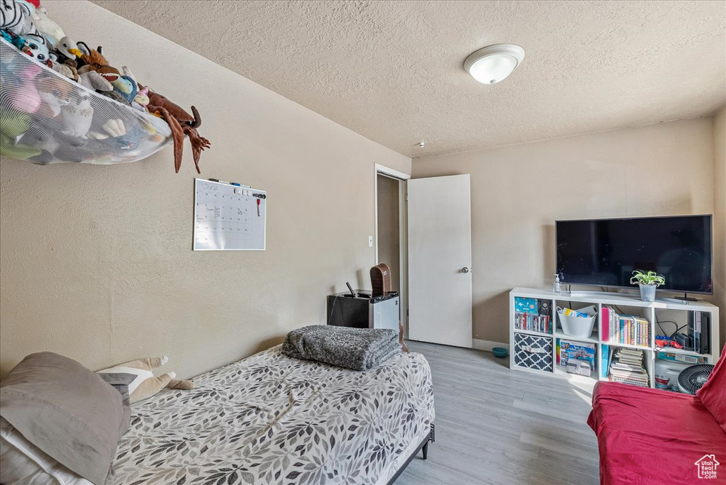 Bedroom with a textured ceiling and wood finished floors