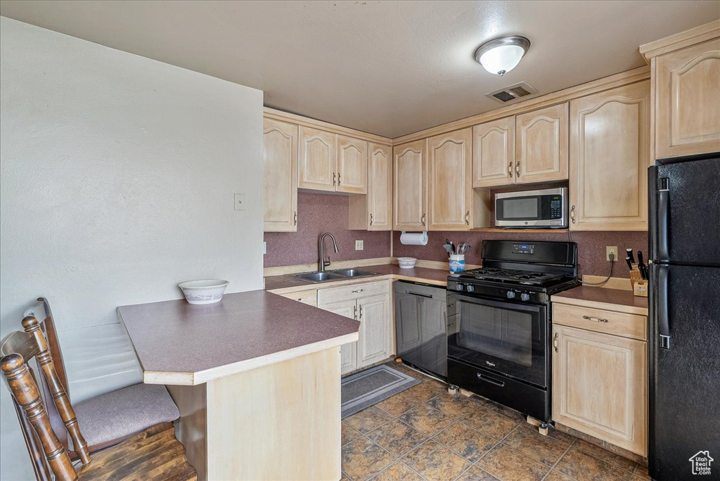 Kitchen with black appliances, light brown cabinets, a peninsula, and a kitchen bar