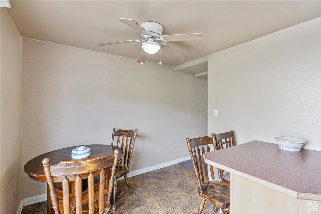 Dining area with ceiling fan and dark stone finish flooring