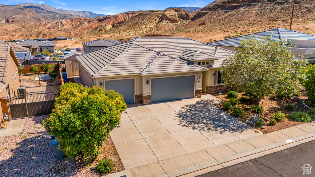 View of front facade with a garage, a gate, driveway, and stucco siding
