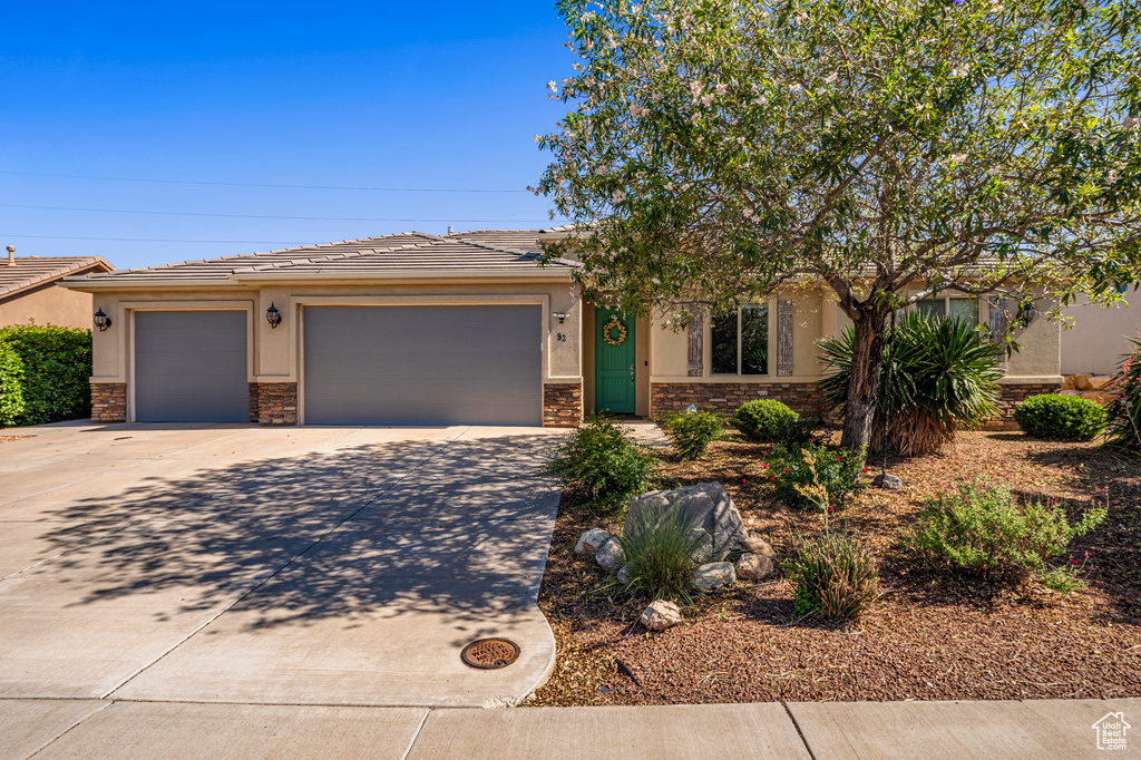 View of front of home with stone siding, stucco siding, concrete driveway, and an attached garage