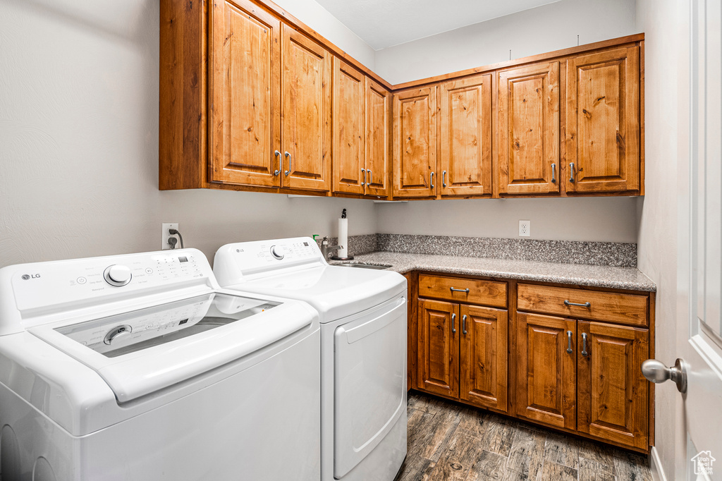 Laundry room featuring independent washer and dryer, cabinet space, and dark wood-type flooring