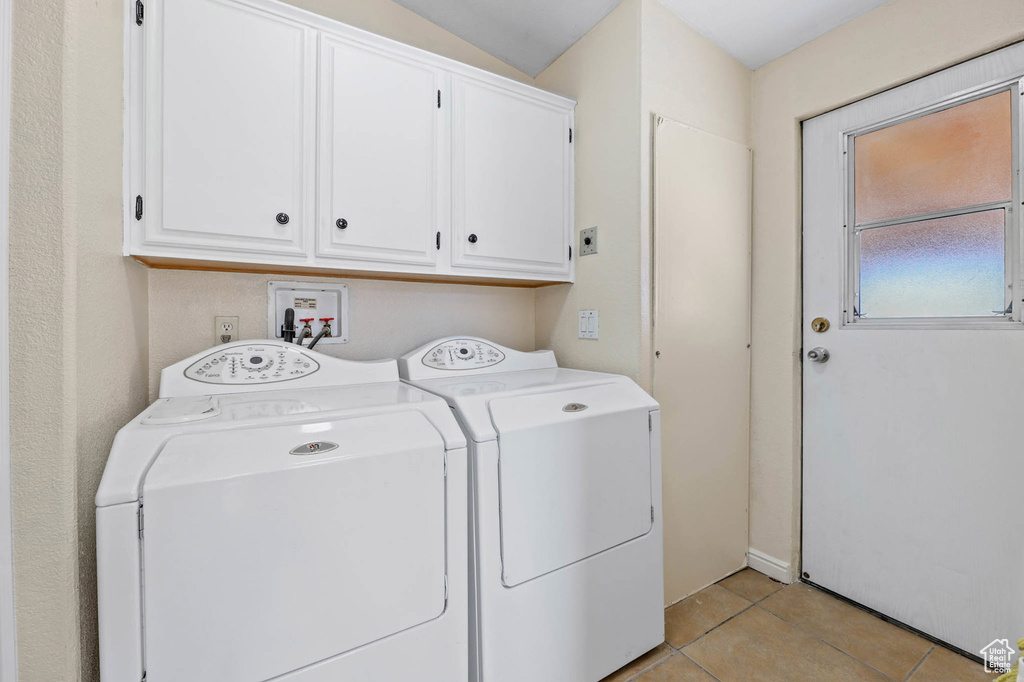 Washroom with cabinet space, light tile patterned floors, and independent washer and dryer
