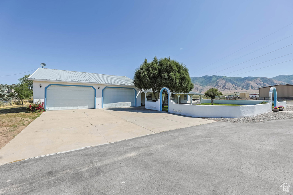 View of front of home with a mountain view, stucco siding, a metal roof, driveway, and an attached garage