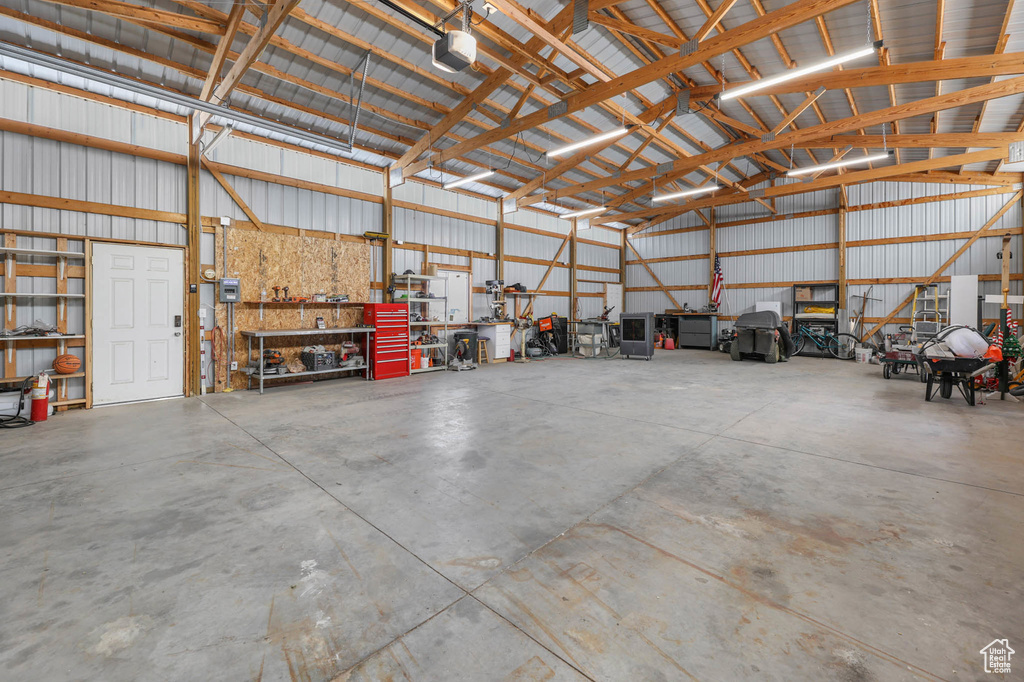 Garage featuring a garage door opener, metal wall, and a workshop area